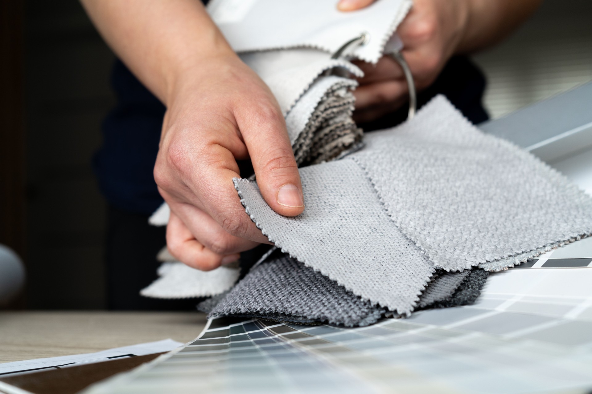 Female interior designer showing furniture fabric material samples to clients in a design studio.